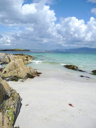 Sandy beach, rocks and blue-green sea on the island of Iona looking towards Mull in the distance © Alistair MacLean