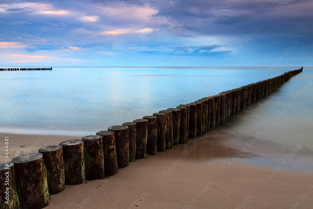 Sandy coast with dramatic sky and pier during sunset. Sandy coast with dramatic sky and pier during sunset.