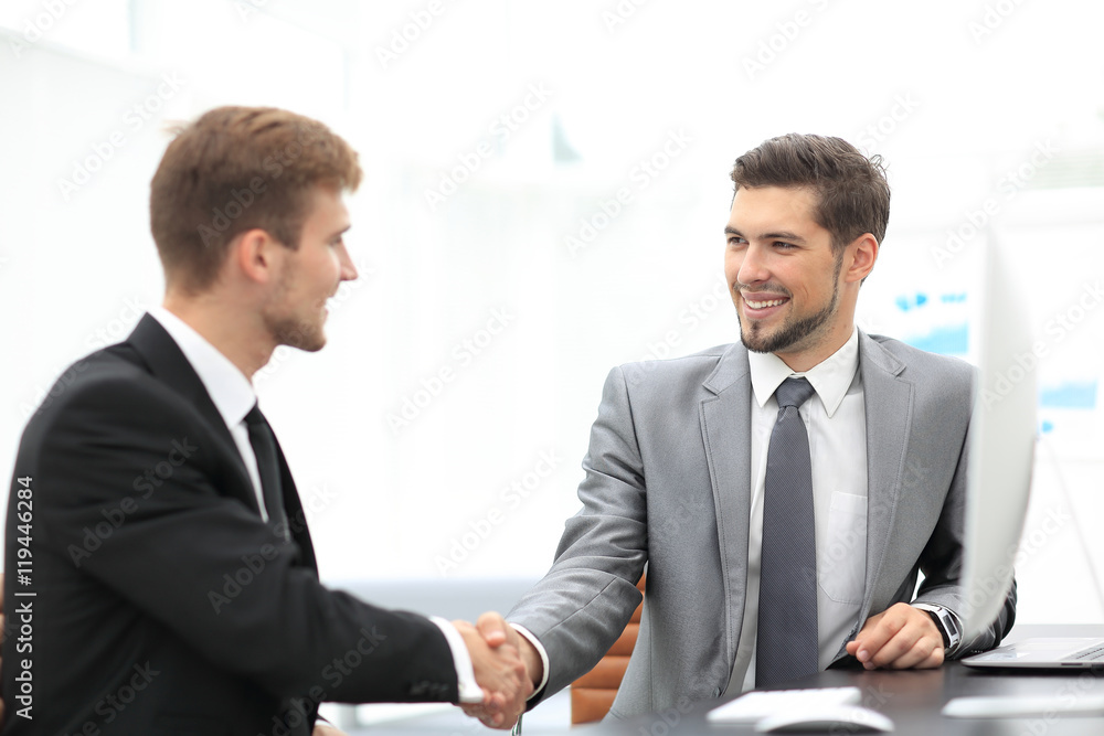 Happy business partners shaking hands in an office Happy business partners shaking hands in an office
