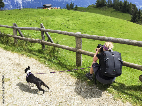 Fotografin wandert mit Kamera und Hund in den Alpen photo