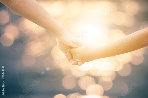 Hands of the mother and baby. Walk hand in hand. Symbolic warmth of family Displaying the love of family, mother and children.On blurred background bokeh nature. Light Fair.