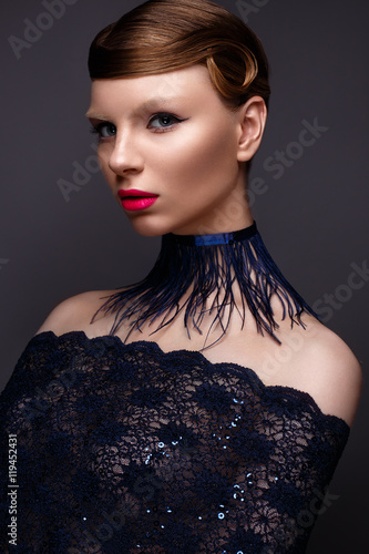 Beautiful girl in the style Gatsby with a collar of feathers and lace blue dress. Model with the hairstyle from the 20s of the 20th century. Beauty face. The photo was taken in a studio.