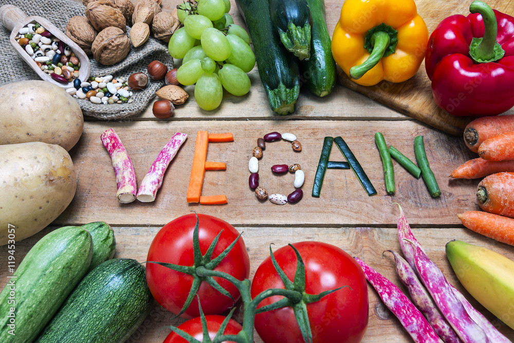 vegan word on wood background and vegetable - food - obrazy, fototapety, plakaty 