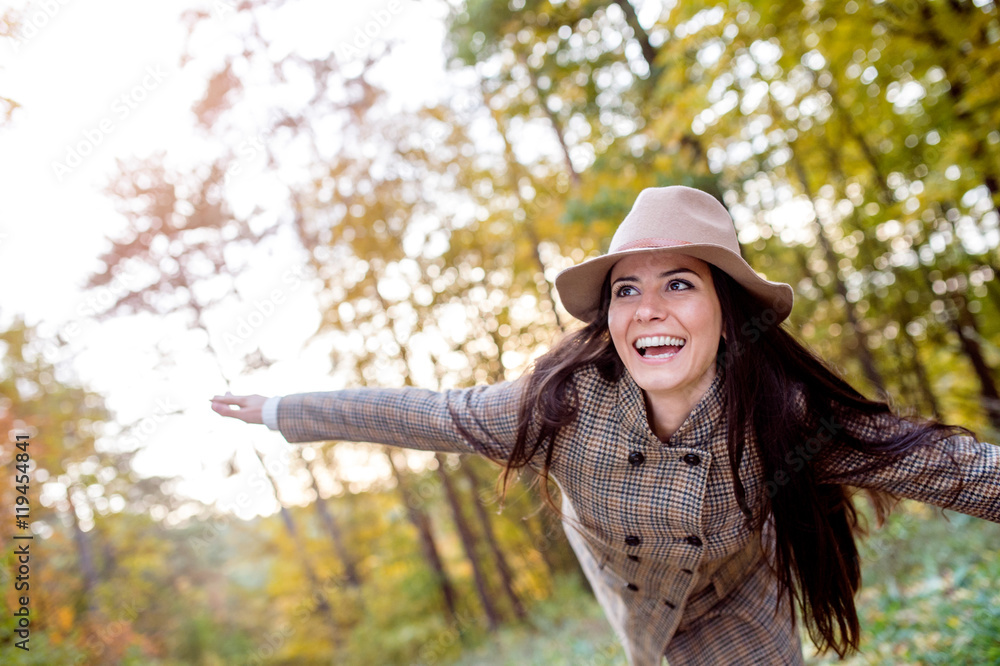 Beautiful woman in checked coat and hat, autumn forest