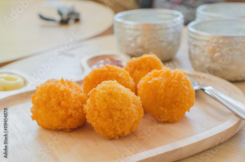 Crispy cheese balls on wood plate, selective focus