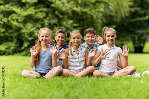 group of happy kids waving hands outdoors