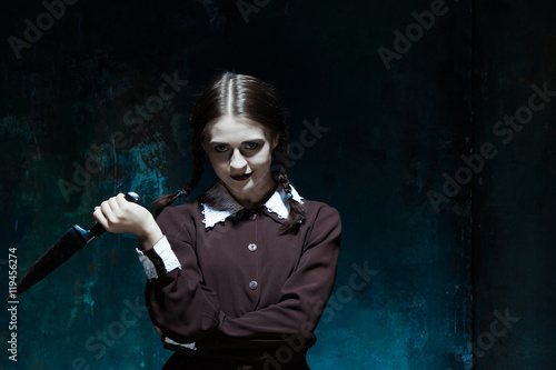 Portrait of a young girl in school uniform as killer woman