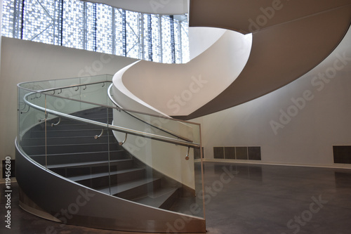 View of the entrance to the spiral staircase of a modern office building. Clear, measured proportions and soft, diffused light through the windows create a feeling of lightness and airiness.