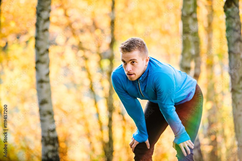 Young handsome hipster runner outside in sunny autumn nature