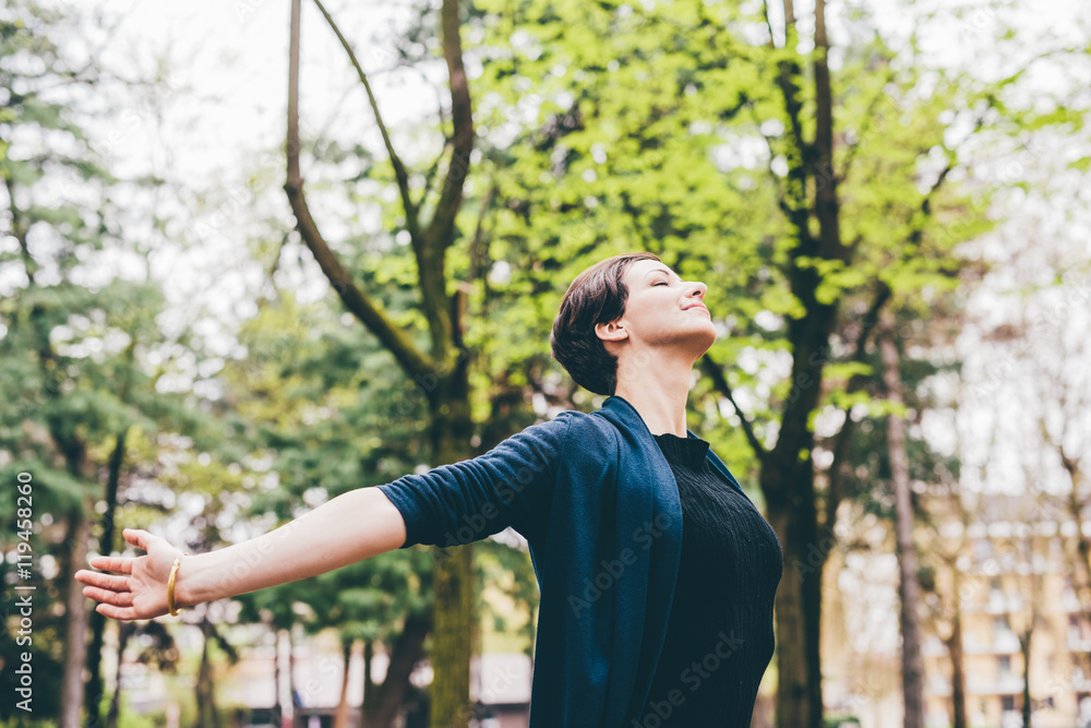 Half length of young beautiful brown hair woman outdoor in the city with arms wide open and eyes closed - relax, freedom, girl power concept Half length of young beautiful brown hair woman outdoor in the city with arms wide open and eyes closed - relax, freedom, girl power concept