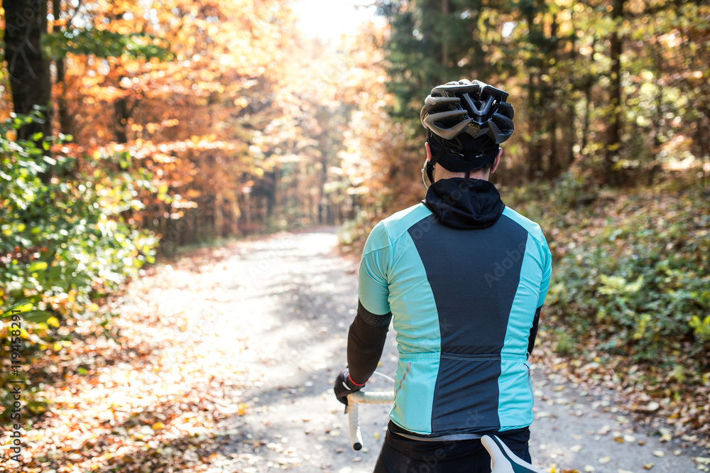 Young sportsman riding his bicycle outside in sunny autumn natur Young sportsman riding his bicycle outside in sunny autumn natur