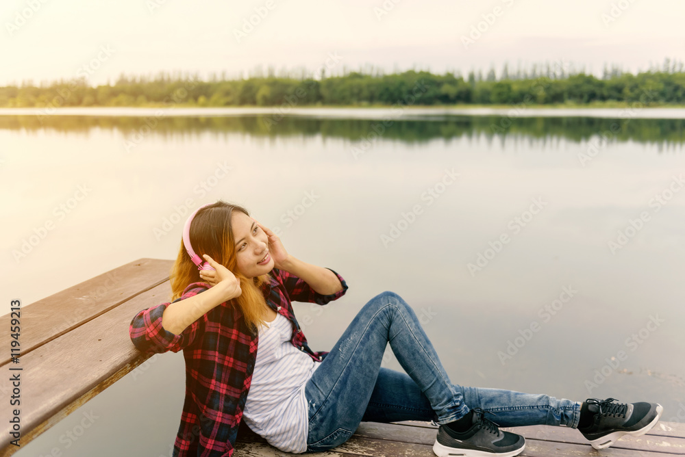 Girl listen to music on wood balcony by river