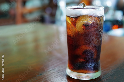 Iced cola with water drops condensed on glass surface, shallow d