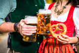 Hände, die Bier und Bretzeln halten, Ausschnitt bayrische Tracht

Hands holding Beer and Pretzels, detail of bavarian Tracht 
