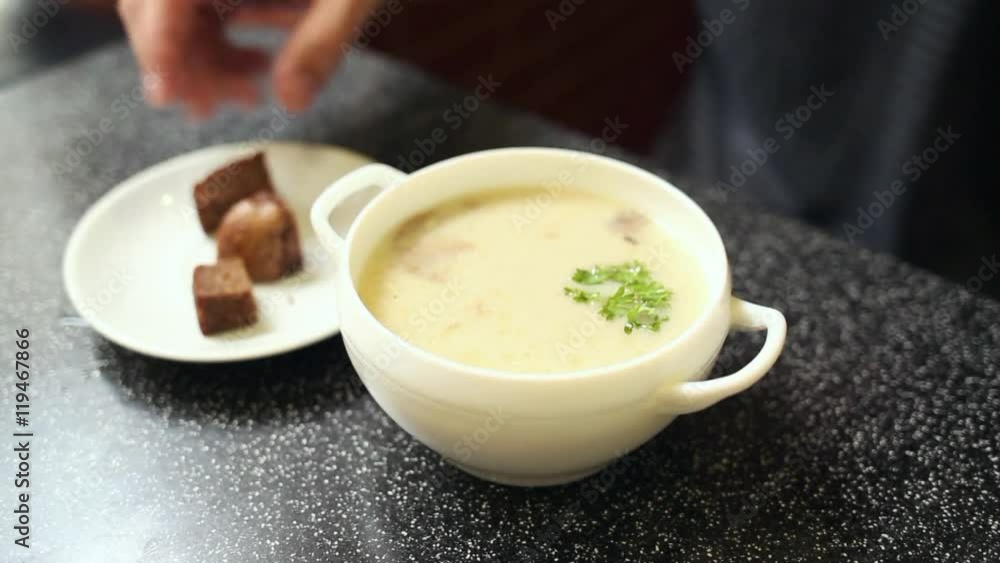 Anonymous man eating in cafe. Close up of male hands holding spoon and bowl with hot cheese soup with sliced champignon mushrooms. Anonymous man eating in cafe. Close up of male hands holding spoon and bowl with hot cheese soup with sliced champignon mushrooms.