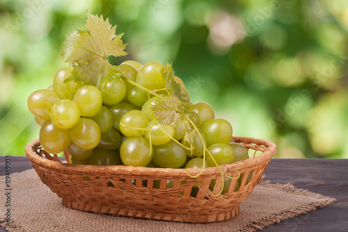 bunch of ripe green grapes on a wooden table with blurred background