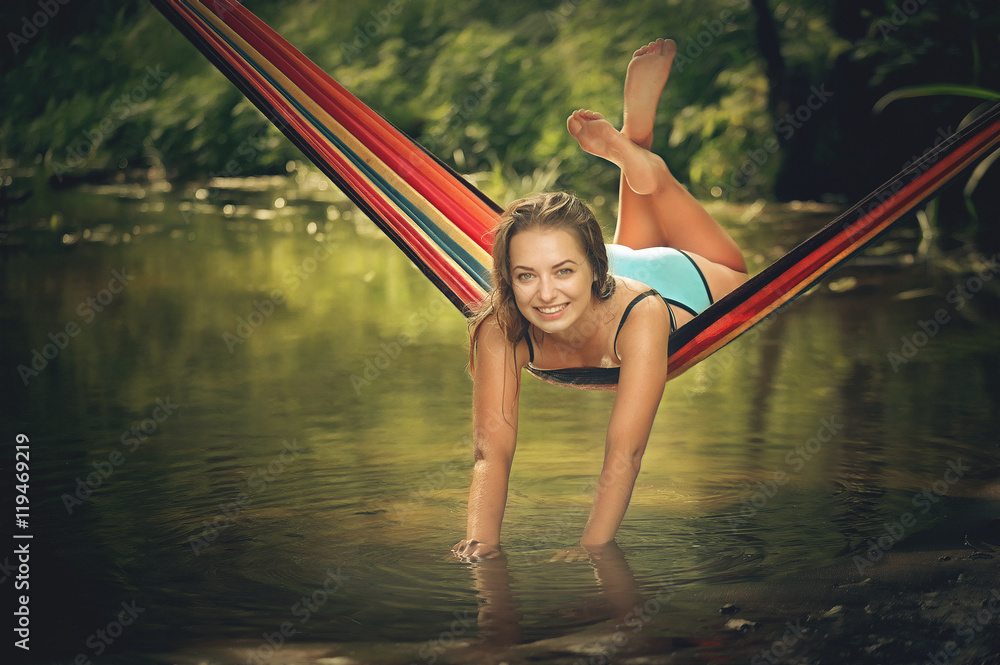 beautiful girl riding in a hammock over the water.
