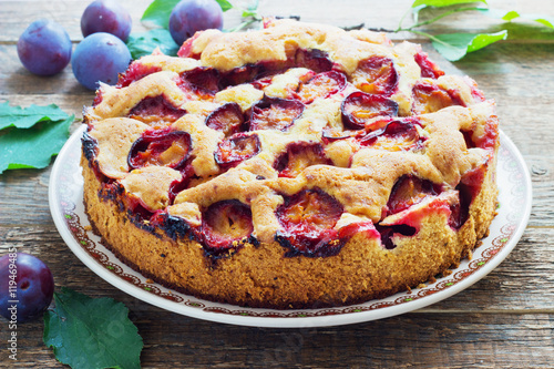 Fotografie rustic plum cake on dark wooden background
