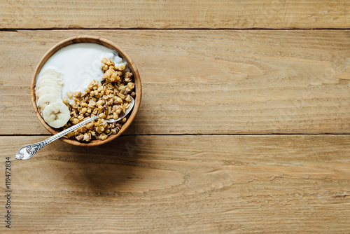 Homemade oatmeal granola with yogurt in wooden bowl