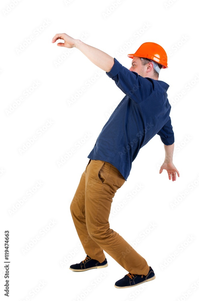 Balancing young man. or dodge the falling man. worker in construction helmet falls. Engineer in protective helmet falls waving his arms.