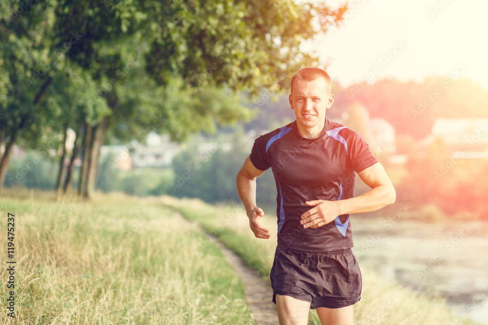 Fototapeta premium Young athletic man jogging in morning park