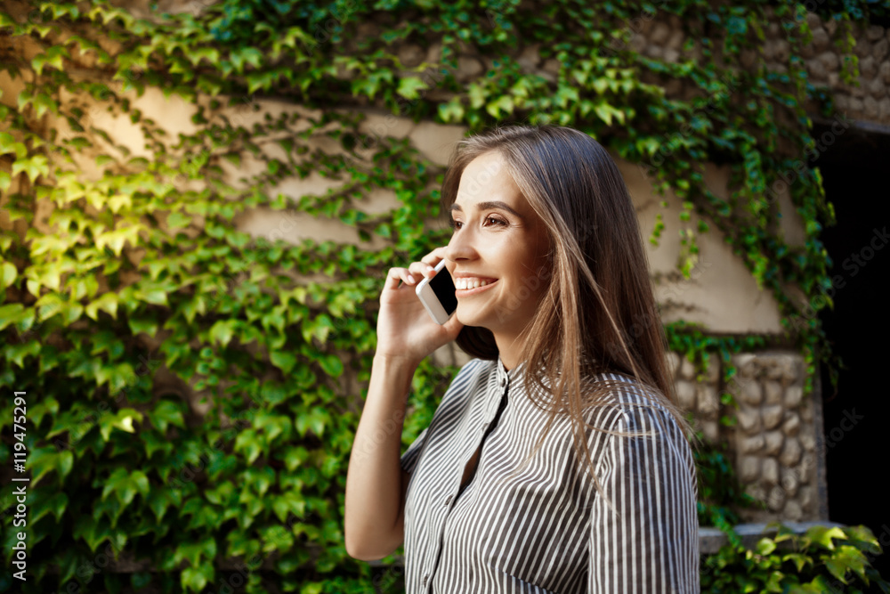 Young beautiful cheerful girl walking around city, speaking on phone. Young beautiful cheerful girl walking around city, speaking on phone.