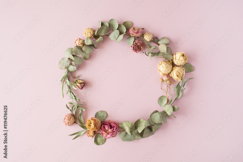 round frame wreath pattern with roses, pink flower buds, eucalyptus branches and leaves on pink background. flat lay, top view