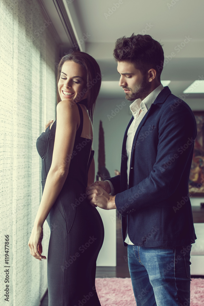 Fototapeta premium Stylish young man helps woman dressing up