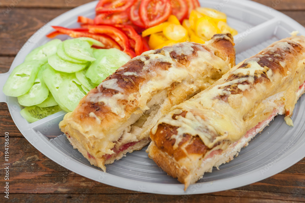 Tasty sandwich with ham, melted cheese and vegetables