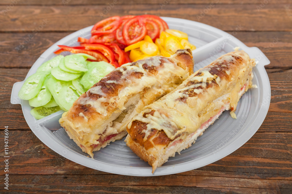 Tasty sandwich with ham, melted cheese and vegetables