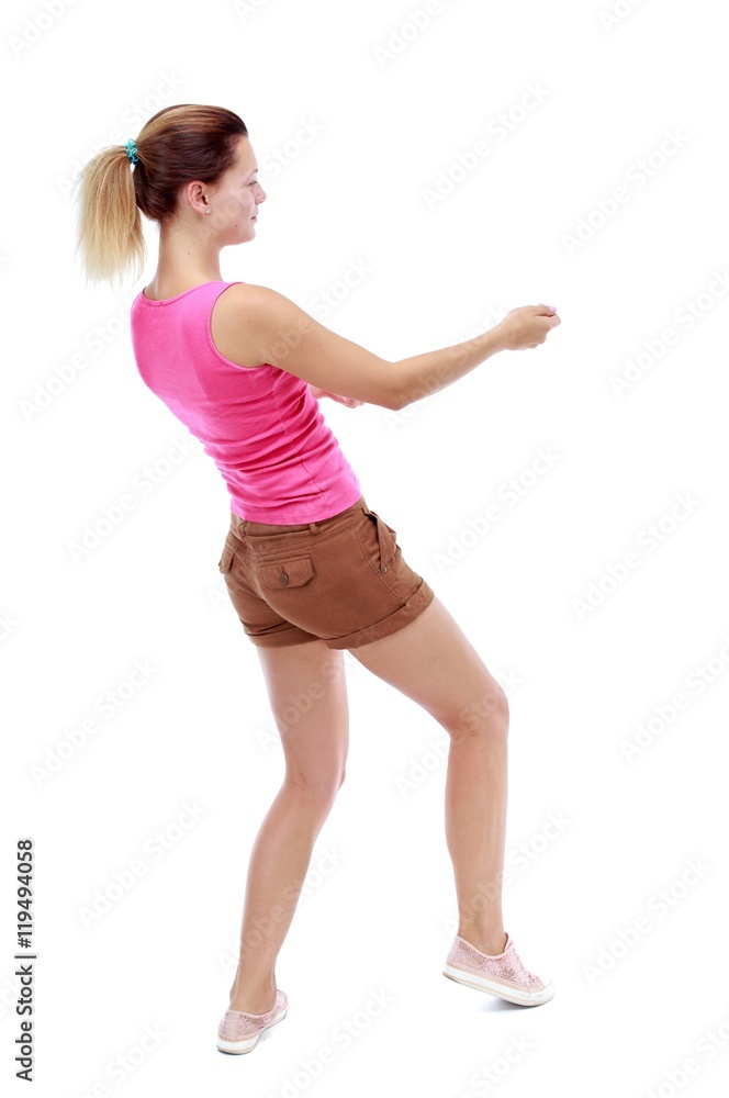back view of standing girl pulling a rope from the top or cling to something. Isolated over white background. Sport blond in brown shorts pulls the rope side. back view of standing girl pulling a rope from the top or cling to something. Isolated over white background. Sport blond in brown shorts pulls the rope side.