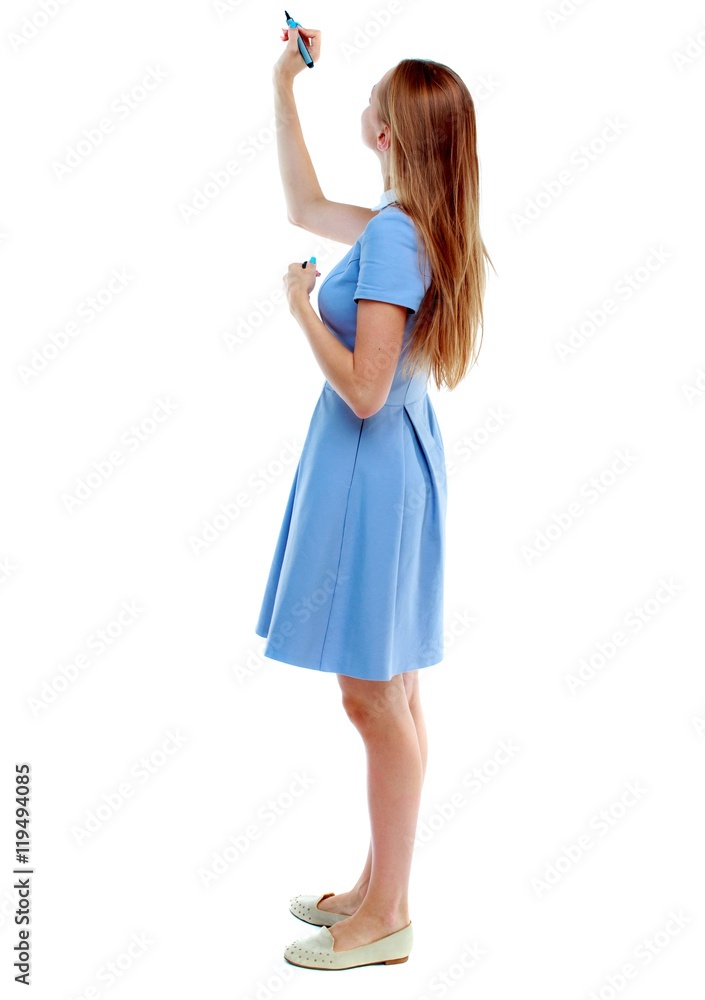 back view of writing beautiful woman. Young girl in dress. Rear view people collection. Isolated over white background. Skinny girl in a blue dress draws a felt-tip pen on top. back view of writing beautiful woman. Young girl in dress. Rear view people collection. Isolated over white background. Skinny girl in a blue dress draws a felt-tip pen on top.