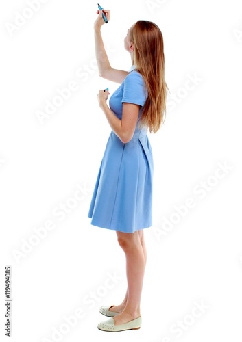 back view of writing beautiful woman. Young girl in dress. Rear view people collection. Isolated over white background. Skinny girl in a blue dress draws a felt-tip pen on top.