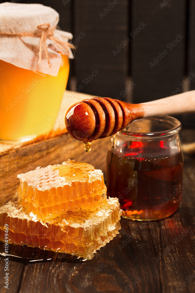 Jar of liquid honey with honeycomb inside over old wooden background. Dark rustic style, selective focus Jar of liquid honey with honeycomb inside over old wooden background. Dark rustic style, selective focus
