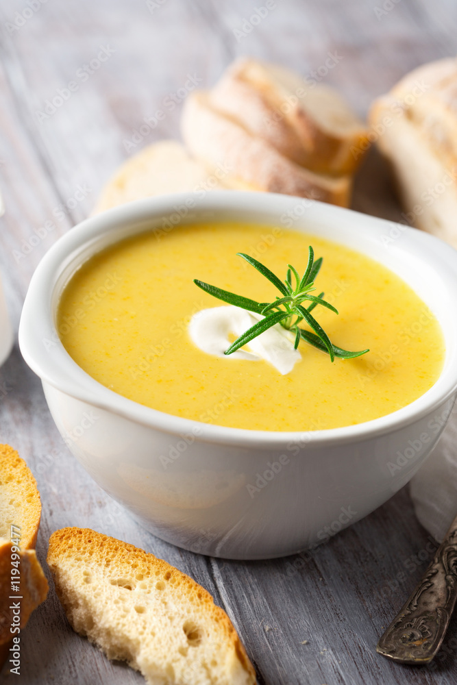 Delicious Vegetable cream soup in a white bowl and bread toasts on rustic wooden table, selective focus Delicious Vegetable cream soup in a white bowl and bread toasts on rustic wooden table, selective focus