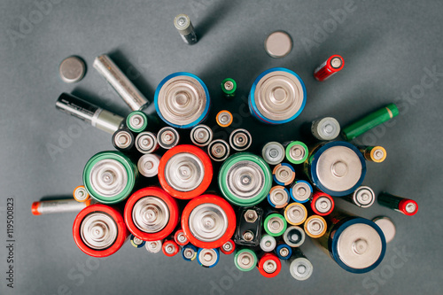 Colorful batteries on gray background, top view. Energy bright backdrop, close-up