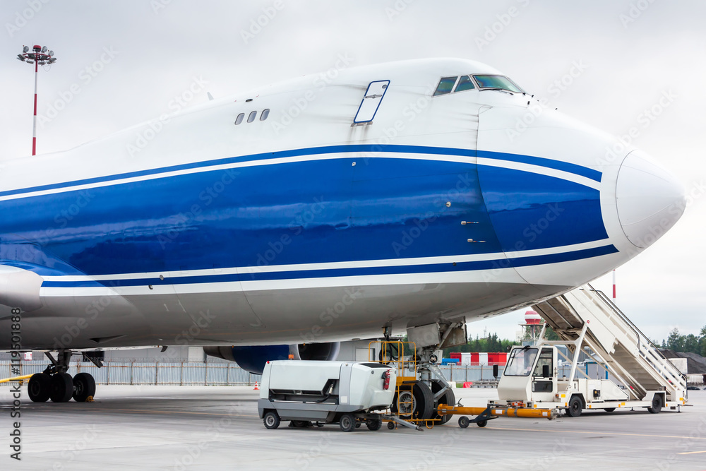 The front of widebody cargo airplane with towbar and passenger step near