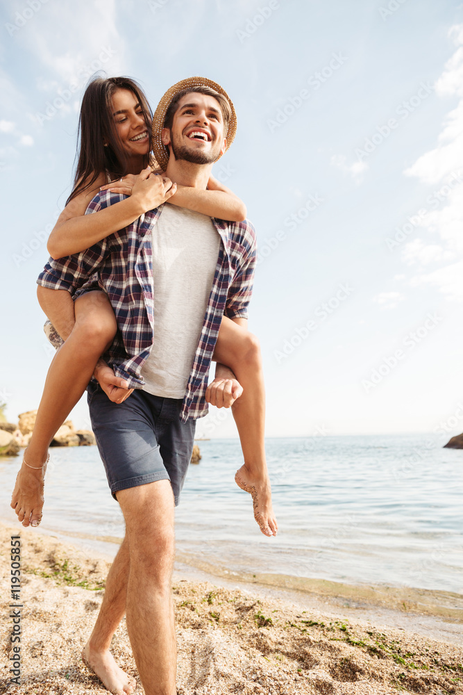 Man giving piggy back ride to his girlfriend at beach Man giving piggy back ride to his girlfriend at beach