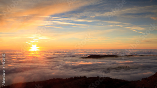Landscape with the sun setting behind clouds and fog © kokophotos