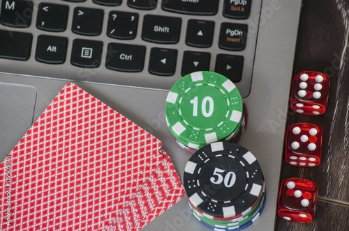 Gambling chips and red dice on laptop keyboard background