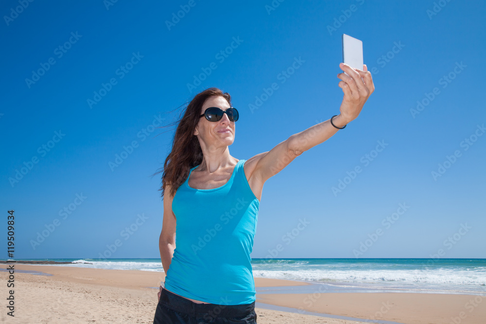 portrait of brunette woman with black sunglasses and blue cyan shirt smiling and making selfie with mobile phone smartphone at beach with sea behind
portrait of brunette woman with black sunglasses and blue cyan shirt smiling and making selfie with mobile phone smartphone at beach with sea behind