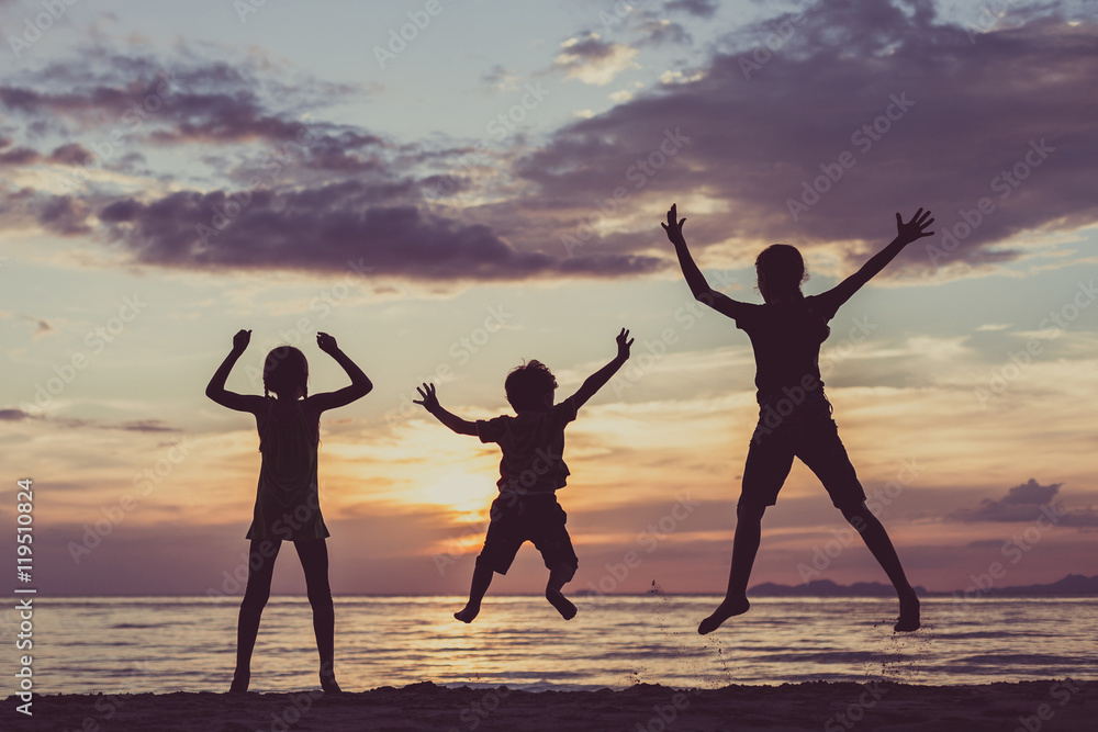 Happy children playing on the beach at the sunset time.