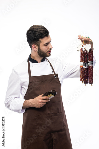 young cheaf with salami in one hand and knife in other hand, sausage department advertising photo