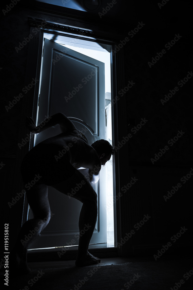 Young adult man peeping through the door Young adult man peeping through the door