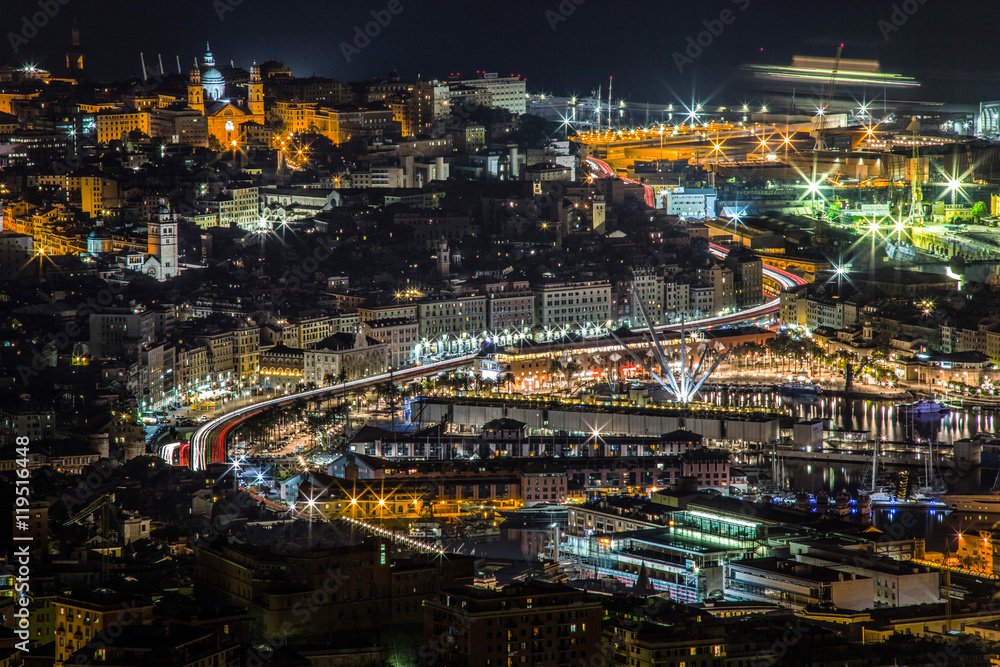 Traffic light trails in Genoa causeway, with skyline of the historic city center buildings and view of the port