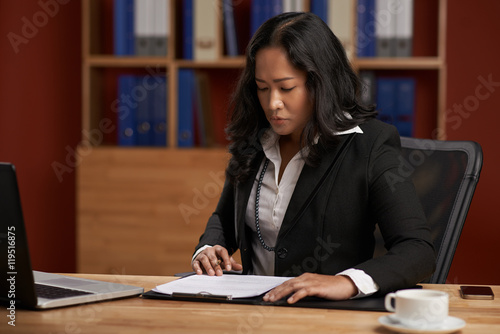 Asian business lady working with papers at her workplace