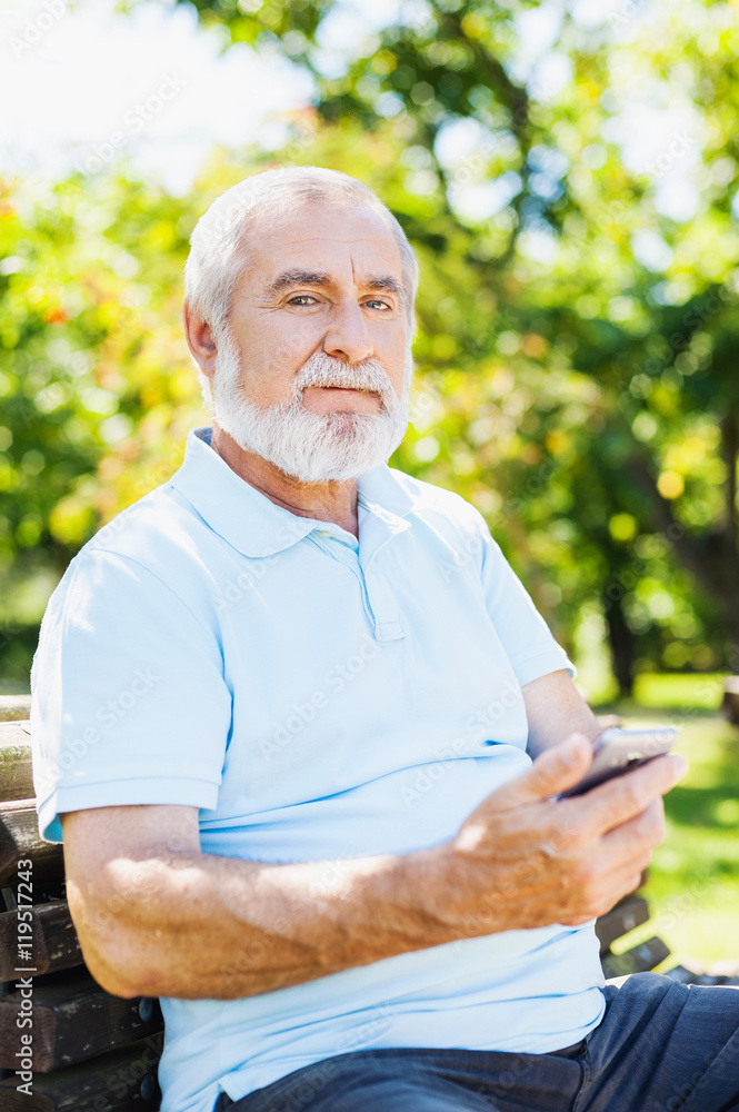 Senior man using smart phone in a park Senior man using smart phone in a park