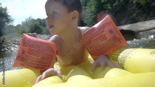 Young Boy Having Fun on Inflatable Mattress in the Mountain River