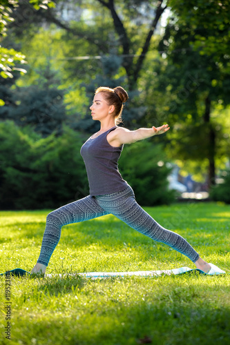 Young woman doing yoga exercises in the summer city park.