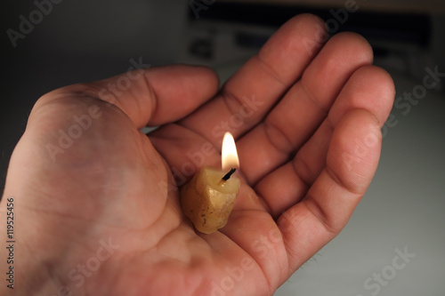 Горящий огарок свечи на ладони